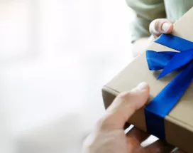 Image shows a person handing a gift to another person