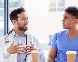 Two doctors and two nurses chatting at a table with coffee