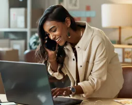 Image shows a woman looking down at her computer and smiling