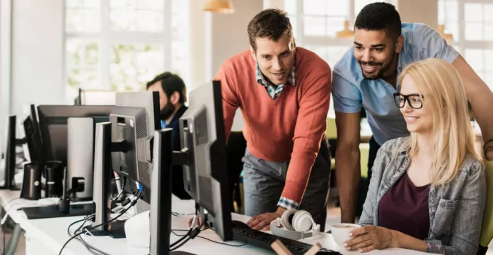 Three employees gathered around a computer