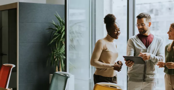 A group of employees working collaboratively together on an tablet.