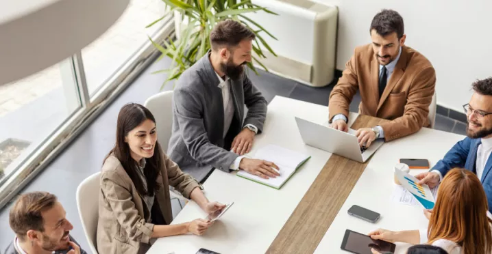 An image of a leadership team going over ways to create a healthy company culture and positive work culture to recognize employees and contribute to business success. They are discussing team building activities to integrate new employees into the organization's culture to create a positive environment and overall thriving culture.