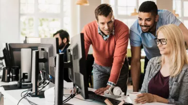 Three employees gathered around a computer