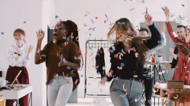 A team celebrating at work with confetti falling down in the background