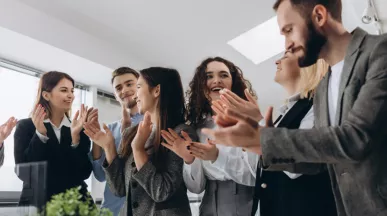A group of employees cheering around a table
