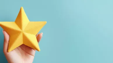 Image shows a hand holding a foam, yellow star.