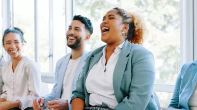 Five employees sitting down laughing on a couch together