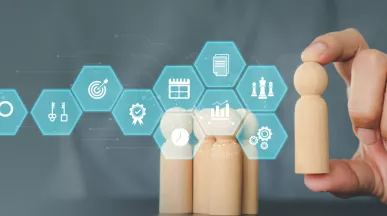 Image shows a person moving a wooden figure with various business symbols in front