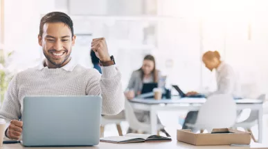 Image shows an employee celebrating by their computer.