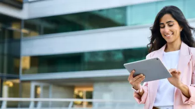 A woman in business clothes smiling down at her tablet