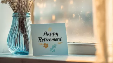 A card that says happy retirement next to a vase with flowers