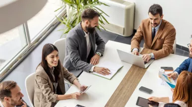 An image of a leadership team going over ways to create a healthy company culture and positive work culture to recognize employees and contribute to business success. They are discussing team building activities to integrate new employees into the organization's culture to create a positive environment and overall thriving culture.
